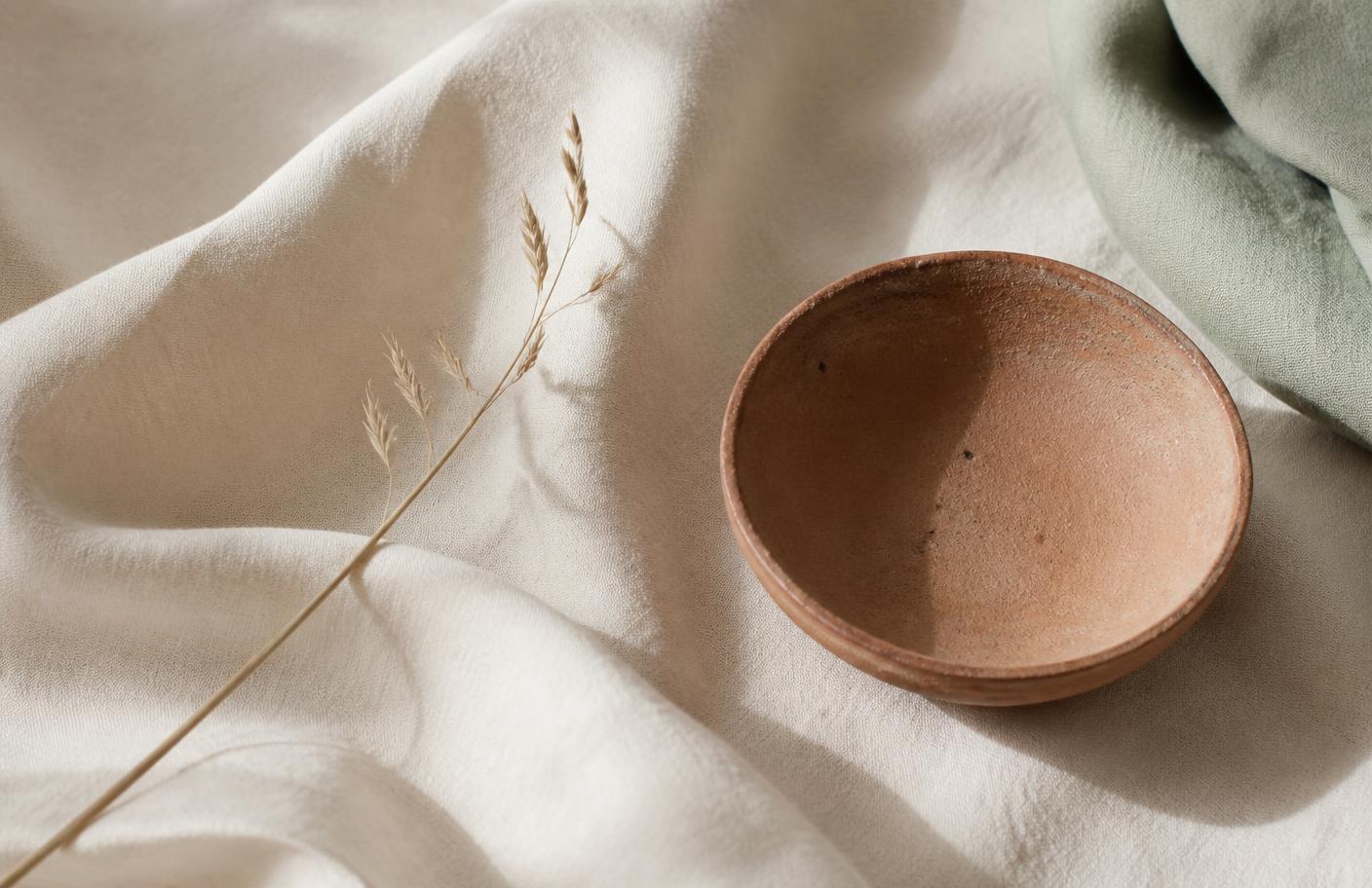 Linnen doek met een gedroogde grasstengel en een terracotta schaaltje